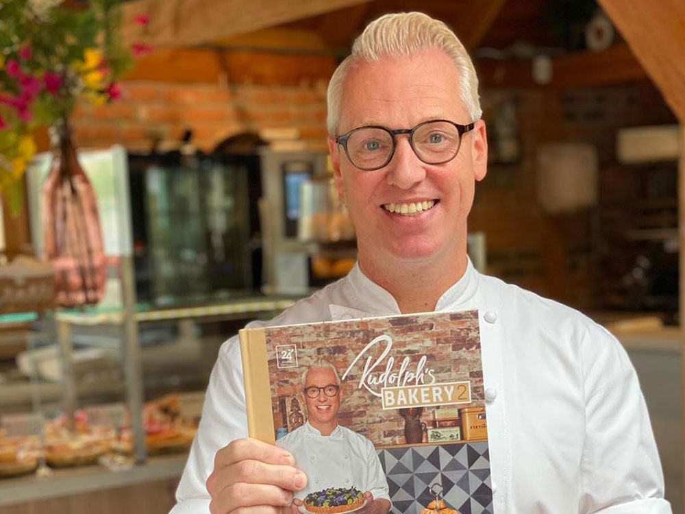 Foto van Rudolph van Veen met boek Rudolphs Bakery 2